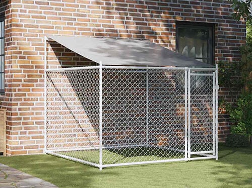 Outdoor galvanised steel dog cage with roof and door placed beside a brick house on grass. Click to see the products in the collection.