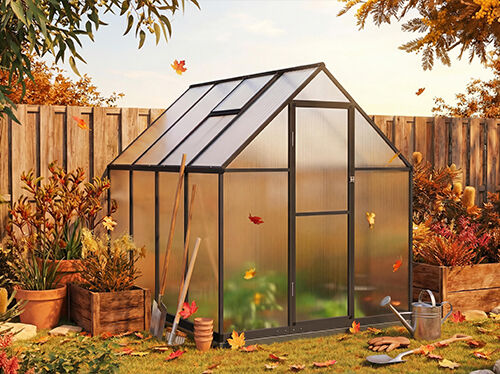 A glass greenhouse stands in a backyard setting surrounded by fallen autumn leaves and wooden planters. Gardening tools are nearby. Click to see the products in the collection. 