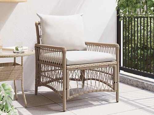 Rattan outdoor armchair with white cushions on a balcony next to a small round side table. Click to see the products in the collection.