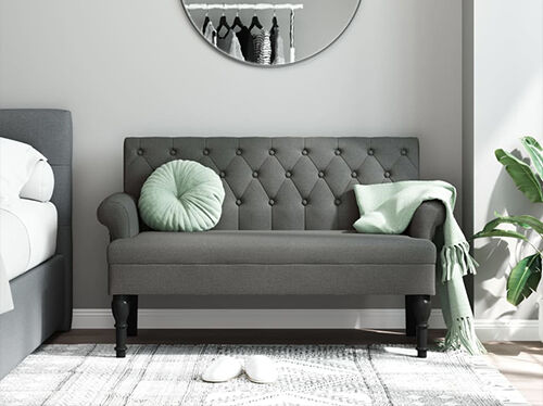 Grey 2-seater sofa with pillow and throw blanket, in a styled bedroom. Click to explore new arrivals.