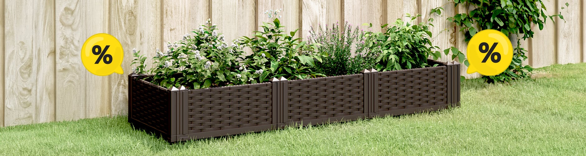 Brown garden planter filled with green plants sitting on green grass against a wooden fence, with two yellow discount bubbles.