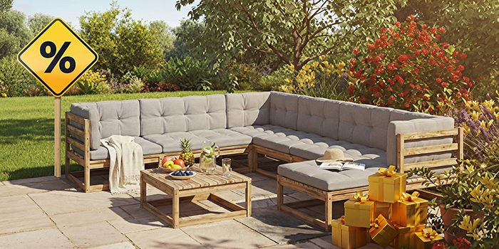 A wooden outdoor furniture set with grey cushions, a matching coffee table, yellow gift boxes, a sign and a clock with discount icons, all on a styled patio. Click to shop the collection.